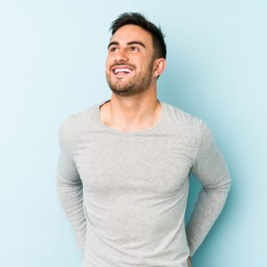 Young caucasian man isolated on blue background relaxed and happy laughing, neck stretched showing teeth.