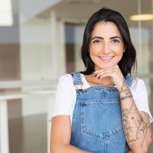 Cheerful woman with hand on chin. Beautiful happy young brunette woman standing with hand on chin and smiling at camera. Gesture concept